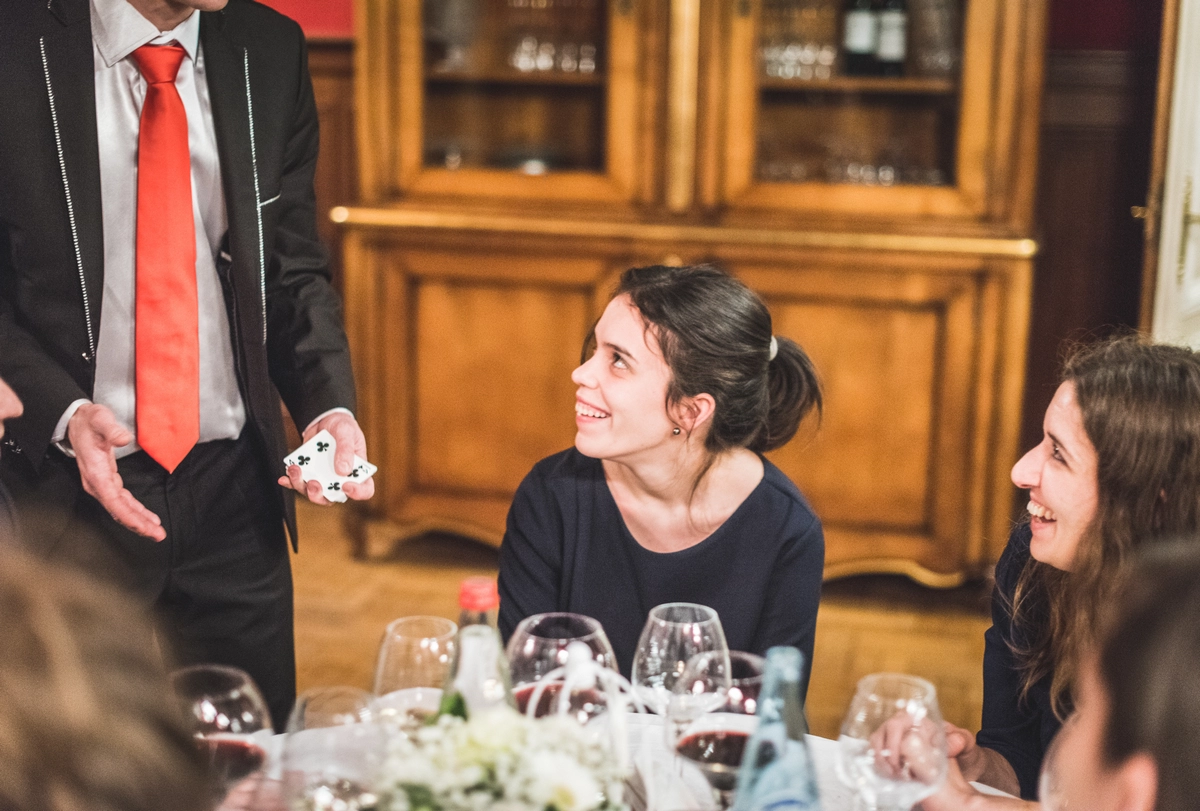 Julien Moreau réalise un tour de magie close-up auprès des invités pendant un dîner